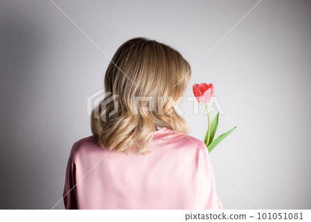 Back view of beautiful woman with tulip flower at gray wall 101051081