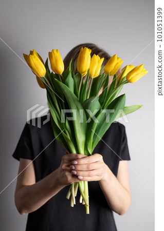 Woman with bouquet of yellow tulips hiding her face Woman with bouquet of yellow tulips hiding her face 101051399