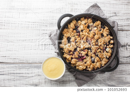 Smulpaj summer berry fruit pie baked with apples and blueberries served with vanilla sauce close-up in a pan. Horizontal top view 101052693