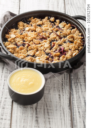 Swedish pie Smulpaj baked with apples and blueberries close-up in a pan. Vertical 101052704