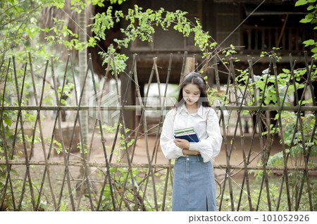 Pretty girl holding some books near a fence 101052926