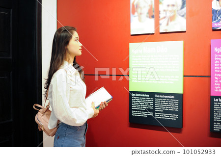 Female student looking at an information board on the red wall Female student looking at an information board on the red wall 101052933