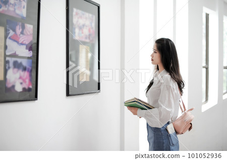 Female student holding some books and looking at an information board Female student holding some books and looking at an information board 101052936