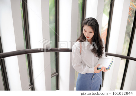 Young pretty woman holding some notebooks and looking downward Young pretty woman holding some notebooks and looking downward 101052944