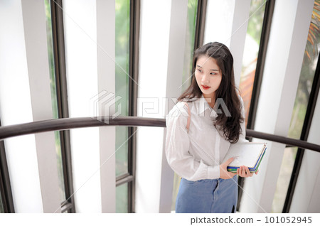 Young pretty woman holding some notebooks and looking aside Young pretty woman holding some notebooks and looking aside 101052945