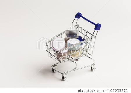 Many colorful natural mineral eyeshadows in toy grocery cart on white background with copy space and empty space for text Many colorful natural mineral eyeshadows in toy grocery cart on white background with copy space and empty space for text 101053871