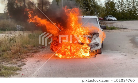 Accident. A white car in an industrial area is on fire. The engine compartment is on fire Accident. A white car in an industrial area is on fire. The engine compartment is on fire 101054760