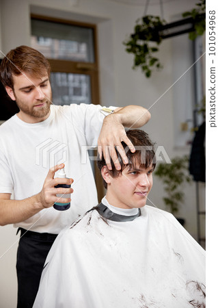 young caucasian man getting haircut by professional male hairstylist young caucasian man getting haircut by professional male hairstylist 101054968