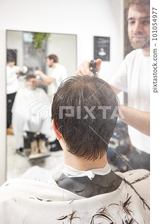 young caucasian man getting haircut by professional male hairstylist 101054977