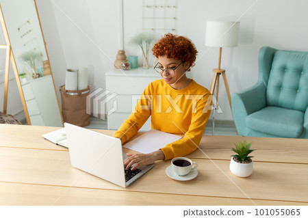African american girl using laptop at home office looking at screen typing chatting reading writing email. Young woman having virtual meeting online chat video call conference. Work learning from home African american girl using laptop at home office looking at screen typing chatting reading writing email. Young woman having virtual meeting online chat video call conference. Work learning from home 101055065