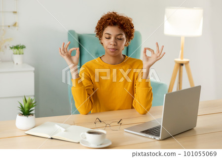 No stress keep calm. Mindful african businesswoman practices breathing exercises at home office. Peaceful young woman at workplace enjoy yoga eyes closed hands in chin mudra gesture. Office meditation No stress keep calm. Mindful african businesswoman practices breathing exercises at home office. Peaceful young woman at workplace enjoy yoga eyes closed hands in chin mudra gesture. Office meditation 101055069