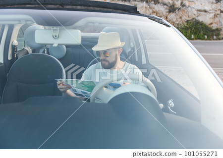 Hipster man looking on location navigation map in car, tourist traveler driving and hold in male hands europe cartography, view and plan tourist way road, trip in transportation cabriolet auto Hipster man looking on location navigation map in car, tourist traveler driving and hold in male hands europe cartography, view and plan tourist way road, trip in transportation cabriolet auto 101055271