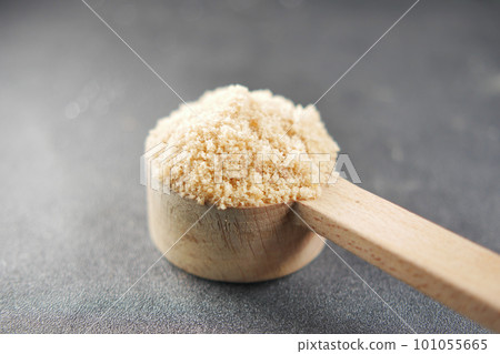 Brown sugar on wooden spoon on table . 101055665