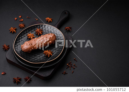 Delicious fresh eclair cake or profiterole with chocolate and nuts 101055712