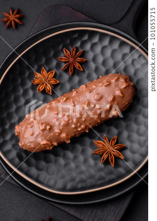 Delicious fresh eclair cake or profiterole with chocolate and nuts 101055715