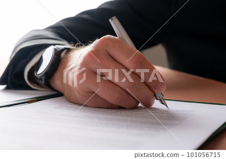 Hand of a businessman with elegant watch on his wrist signing a document 101056715