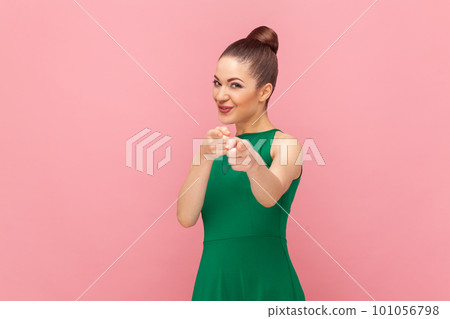 Portrait of smiling satisfied flirting woman standing and pointing to camera with positive expression, need you, wearing green dress. Indoor studio shot isolated on pink background. Portrait of smiling satisfied flirting woman standing and pointing to camera with positive expression, need you, wearing green dress. Indoor studio shot isolated on pink background. 101056798