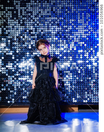little girl with pigtail in a black long curvy dress at the disco. shiny wall 101056966