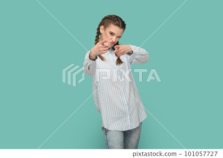Portrait of positive optimistic flirting teenager girl with braids wearing striped shirt pointing fingers to camera, choosing you. Indoor studio shot isolated on green background. 101057727