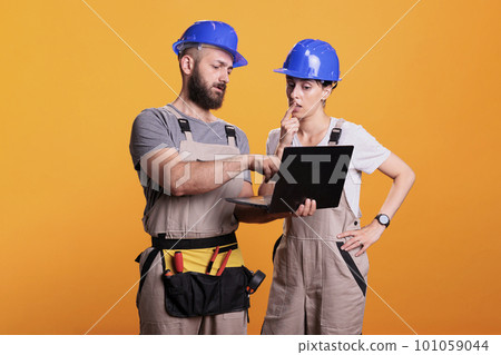 Renovators team holding laptop and browsing internet online, discussing about renovation project. Construction workers using wireless pc to search building inspiration, studio shot. Renovators team holding laptop and browsing internet online, discussing about renovation project. Construction workers using wireless pc to search building inspiration, studio shot. 101059044