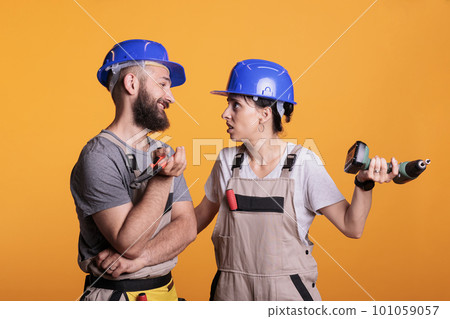 Engineering partners talking about different ideas for construction project, doing teamwork on renovation. Team of renovators working together using drill gun and pair of pliers in studio. Engineering partners talking about different ideas for construction project, doing teamwork on renovation. Team of renovators working together using drill gun and pair of pliers in studio. 101059057