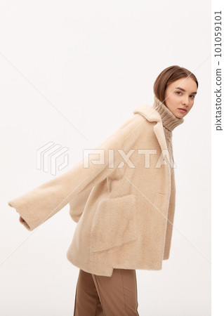Close-up of a modern business woman on a light background in fashionable faux fur clothes, fashion, modern urban style 101059101
