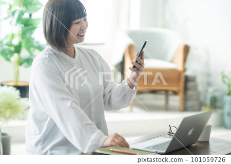 A woman in her 30s working from home in the living room A woman in her 30s working from home in the living room 101059726