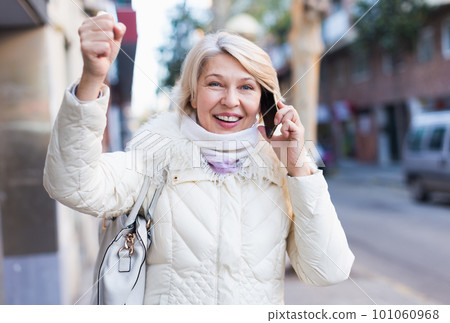 Smiling mature woman talking on phone and hand up 101060968