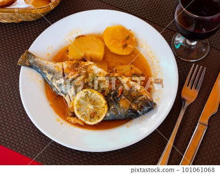 Baked in oven dorado fish with lemon and potatoes served on plate closeup 101061068