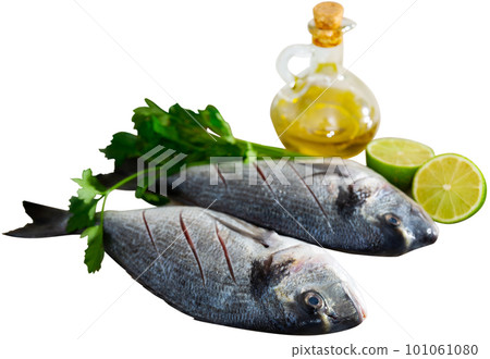 Two raw doradas served on table with herbs lime salt and oil 101061080