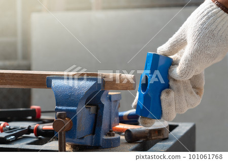 Male hobby retirement. Senior man is using bench vise on wood for assembling hammer handle. Male hobby retirement. Senior man is using bench vise on wood for assembling hammer handle. 101061768