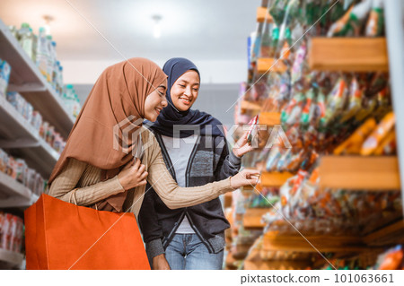 Two Muslim girls pick up a item on a shelf Two Muslim girls pick up a item on a shelf 101063661