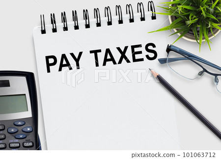 PAY TAXES Text on notepad and calculator,pencil on white office desk background. T PAY TAXES Text on notepad and calculator,pencil on white office desk background. T 101063712