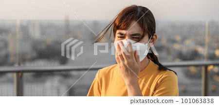 young Asian woman wearing N95 respiratory mask protect and filter pm2.5 or particulate matter against bad Air Pollution in City. Air Quality Index, AQI, Unhealthy, healthcare concept young Asian woman wearing N95 respiratory mask protect and filter pm2.5 or particulate matter against bad Air Pollution in City. Air Quality Index, AQI, Unhealthy, healthcare concept 101063838