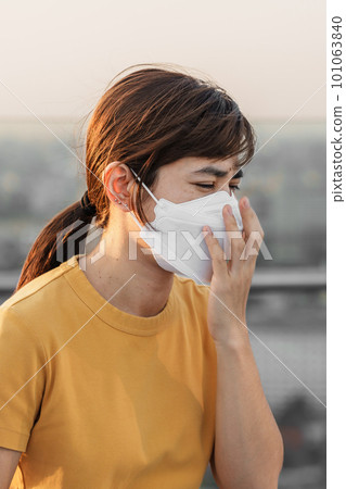 young Asian woman wearing N95 respiratory mask protect and filter pm2.5 or particulate matter against bad Air Pollution in City. Air Quality Index, AQI, Unhealthy, healthcare concept 101063840