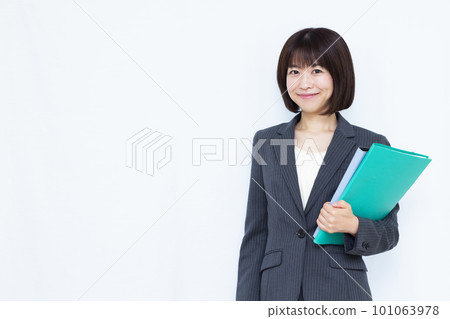 三十多歲的女商人穿著西裝，在白色背景前拿著一份文件 101063978