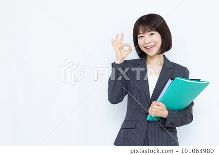 Business woman in her thirties in a suit doing okay in front of a white background 101063980