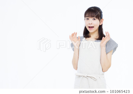 一位 30 多歲的家庭主婦穿著圍裙，在白色背景前感到驚訝 101065423