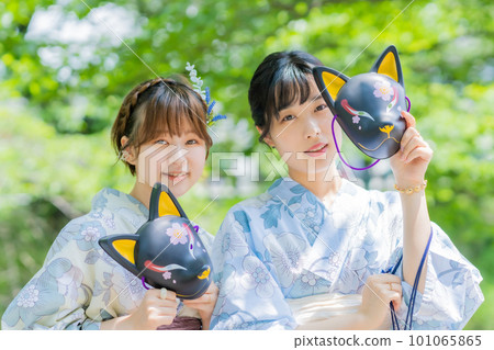 A young woman posing in a yukata with the mask of a summer festival in her hand 101065865