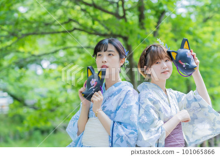 A young woman posing in a yukata with the mask of a summer festival in her hand 101065866