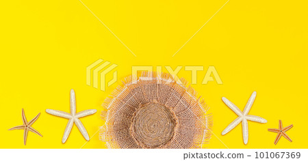 Beach hat made of burlap with sea white and brown starfish on yellow background. Banner. Concept of summer, vacation. Copy space Beach hat made of burlap with sea white and brown starfish on yellow background. Banner. Concept of summer, vacation. Copy space 101067369