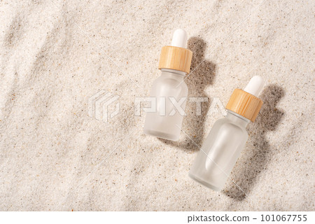 Glass bottles with a cosmetic product on a natural sandy background. Top view. 101067755
