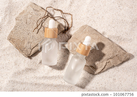 Glass bottles with a cosmetic product on a natural sandy background. Top view. Glass bottles with a cosmetic product on a natural sandy background. Top view. 101067756