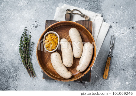 Bavarian white sausage in wooden plate with mustard. Gray background. Top view Bavarian white sausage in wooden plate with mustard. Gray background. Top view 101069246