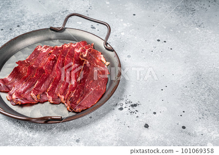 Sliced basturma, cured beef meat in steel tray. Gray background. Top view. Copy space Sliced basturma, cured beef meat in steel tray. Gray background. Top view. Copy space 101069358