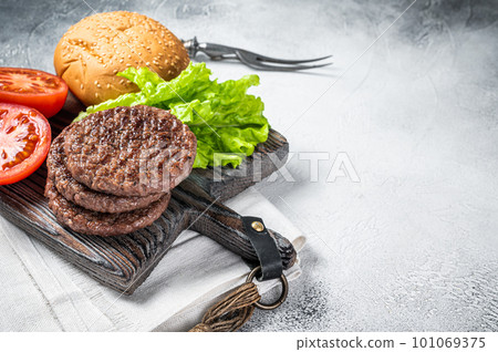 Fried cutlet for burger with vegetables and spices on wooden board. White background. Top view. Copy space Fried cutlet for burger with vegetables and spices on wooden board. White background. Top view. Copy space 101069375