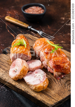 Roast Chicken roll with cheese and herbs on a wooden board. Dark background. Top view Roast Chicken roll with cheese and herbs on a wooden board. Dark background. Top view 101069389