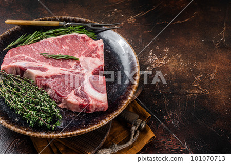 Dry aged Raw porterhouse beef meat Steak, fresh T bone on rustic plate with spices. Dark background. Top view. Copy space 101070713