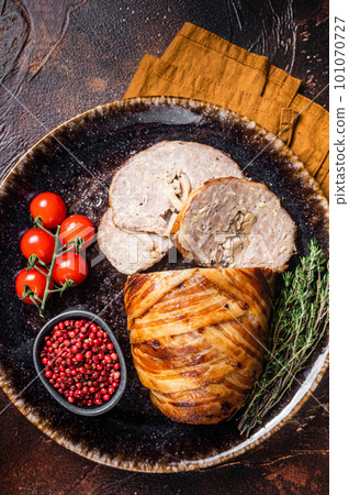 Baked delicious beef meatloaf, sliced meat loaf with bacon and herbs on a plate. Dark background. Top view Baked delicious beef meatloaf, sliced meat loaf with bacon and herbs on a plate. Dark background. Top view 101070727