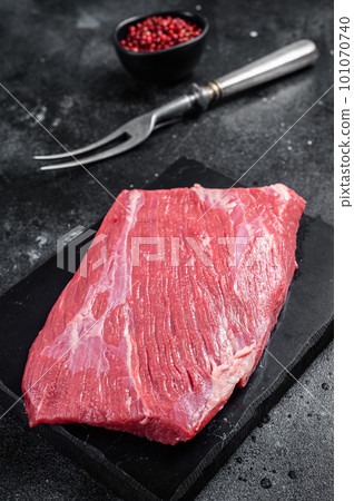 Prime choice flank steak, raw beef meat on marble board with herbs. Black background. Top view 101070740